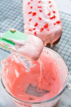 a spoon full of pink frosting being stirred by a mixer