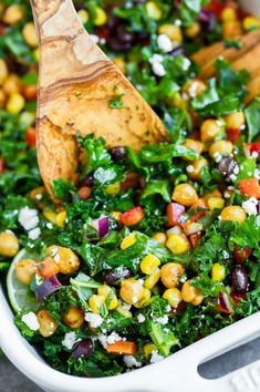 a salad in a white dish with a wooden spoon