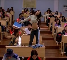 a woman standing on top of desks in a classroom