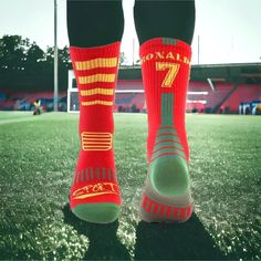 the legs and feet of a soccer player wearing red socks with yellow numbers on them