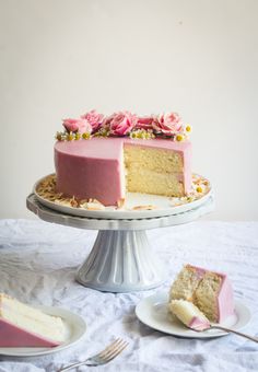 a white cake with pink frosting and flowers on top, sitting on a table