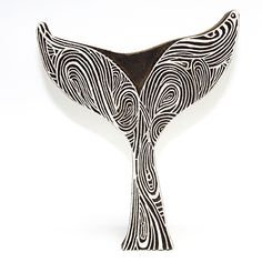 a black and white vase sitting on top of a table in the shape of a whale's tail