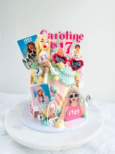 a birthday cake decorated with barbie dolls and photos on it's side, sitting on a white plate