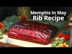 a large piece of meat sitting on top of a cutting board next to flowers and pineapples