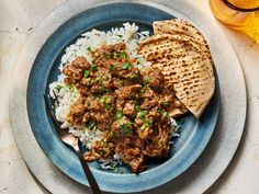 a plate with rice, meat and pita bread on it next to a glass of beer