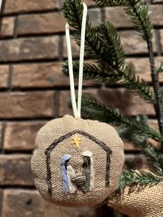 a christmas ornament hanging from a tree with a brick wall in the background