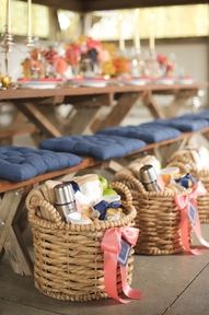 the picnic table is set up with blue cushions and wicker baskets filled with food