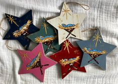 five wooden star ornaments hanging from twine on a white cloth covered tablecloth with gold and blue designs