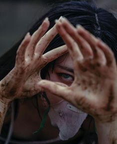 a woman covered in mud holding her hands up