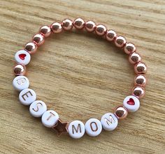 Hello and welcome. Mother's Day bracelets. You can build your own from Bead sample picture or choose one of my displays. I offer wooden beads, silver, gold, rose gold, dark gold and brownish gold beads. Also light pink pearl beads. As accents I offer heart shape beads in silver and rose gold. Start is gold, rose and silver. Round heart beads in red, blue, pink and black. Letter choice is white/black or white/rose gold. Each bracelet is stretchy and will come in an organza bag ready for gift givi Mom Bead Bracelets, Mothers Day Bracelet Ideas, Mom Bracelet Ideas, Mother’s Day Bracelet Ideas, Mothers Day Bracelets Diy, Mother's Day Gift Rose Gold Charm Bracelet, Personalized Name Beaded Bracelets For Mother's Day, Personalized Mother's Day Beaded Name Bracelets, Personalized Beaded Bracelets For Mother's Day Birthday Gift