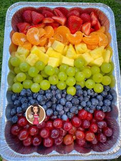 a tray filled with grapes, oranges and strawberries on top of each other