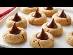 some cookies with chocolate on top are sitting on a white plate, ready to be eaten