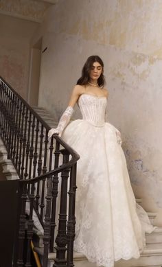 a woman in a wedding dress standing on the stairs