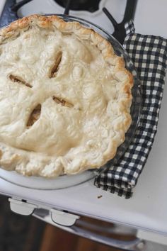 a pie sitting on top of a white table next to a black and white checkered napkin