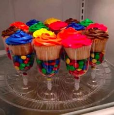 there are cupcakes with candy in them on the glass plate, ready to be eaten