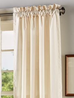 a curtain with ruffled edges hanging in front of a window, next to a framed photograph