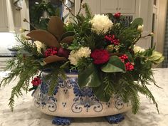 a blue and white vase filled with flowers on top of a marble counter topped with greenery