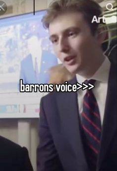 a man wearing a suit and tie standing in front of a screen with the words baron's voice on it