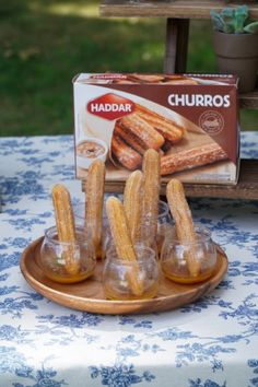 churros sitting on a plate with glasses in front of it and a box of churros behind them