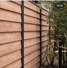 the side of a house with wood siding and black iron fence post in front of it