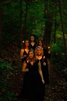 a group of women holding candles in the woods