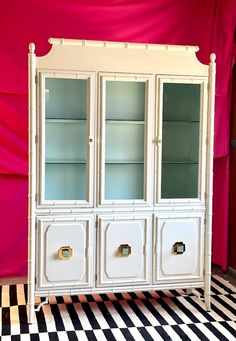 a white china cabinet sitting on top of a checkered floor