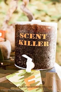 a can of scent killer sitting on top of a camouflage covered table with other items