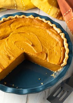 a pumpkin pie on a blue plate with a slice missing from it's crust