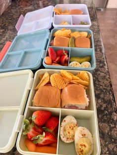 several trays filled with different types of food on top of a marble countertop