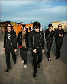 a group of young men walking down a street next to eachother wearing sunglasses