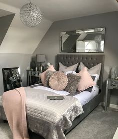 a bedroom with grey walls and white bedding, pink pillows and gray throw pillows