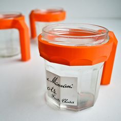 three jars with orange lids and labels on them