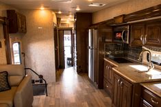 a kitchen and living room area in a recreational vehicle or motor home with wood flooring