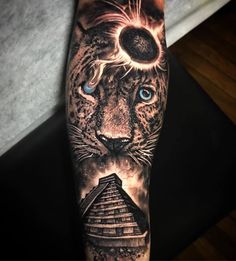 a man's arm with a tiger and pyramid tattoo on it