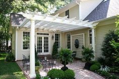 an outdoor patio with chairs and tables in front of a house