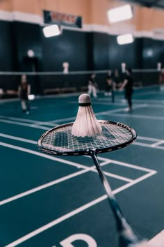 a badminton racket is on the court with people playing tennis in the background,