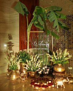 a table topped with vases filled with flowers and greenery next to a sign