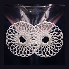 two white crocheted earrings hanging from hooks