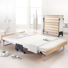 a bed that is in the middle of a room with white walls and flooring