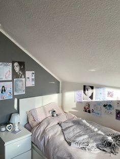 a white bed sitting under a window next to a wall with pictures hanging on it