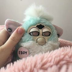 a person holding a small stuffed animal in their hand with the word eboy on it