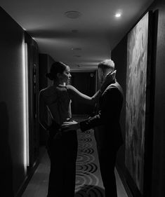 a man helping a woman put on her dress in the hallway at an event or conference