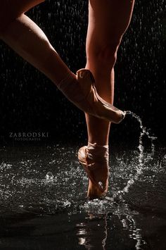 a woman's feet in the water with rain coming down on her and she is wearing ballet shoes