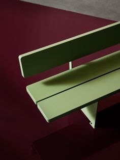 a green bench sitting on top of a red floor