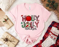 Celebrate the holiday spirit with our Holly Jolly Teacher Christmas T-Shirt!  This festive tee is designed especially for educators who bring joy and inspiration to their classrooms. Featuring a cheerful holiday design, this shirt is perfect for teachers who want to spread some Christmas cheer while remaining comfortable and stylish. Made from high-quality, soft fabric, our T-shirt offers a relaxed fit that is perfect for layering or wearing on its own. Whether you're attending a school holiday School Holiday Party, Christmas Apparel, Teacher Sweatshirt, School Holiday, Teacher Tees, Teacher Christmas, School Holidays, Teacher Favorite Things, Teacher Tshirts