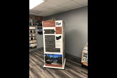 an advertisement board in the middle of a room with wood floors and tile flooring