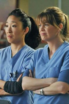 two women in scrubs standing next to each other with their arms crossed and looking at the camera