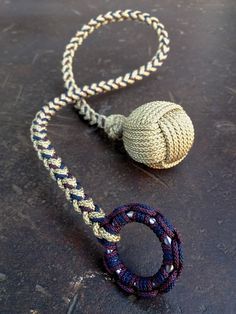 a rope with a ball attached to it on top of a wooden table next to a metal object