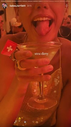 a woman sticking her tongue out and holding a wine glass with the word extra dirty written on it