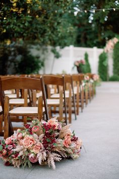 an aisle lined with wooden chairs and flowers